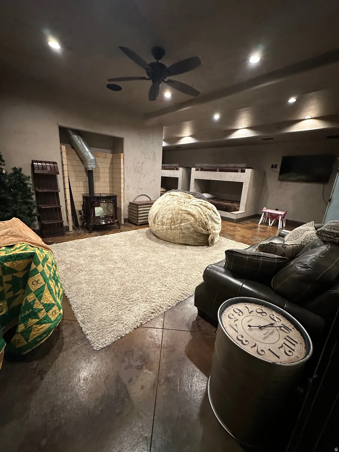 Living room with finished concrete flooring, a pellet stove, recessed lighting, and ceiling fan