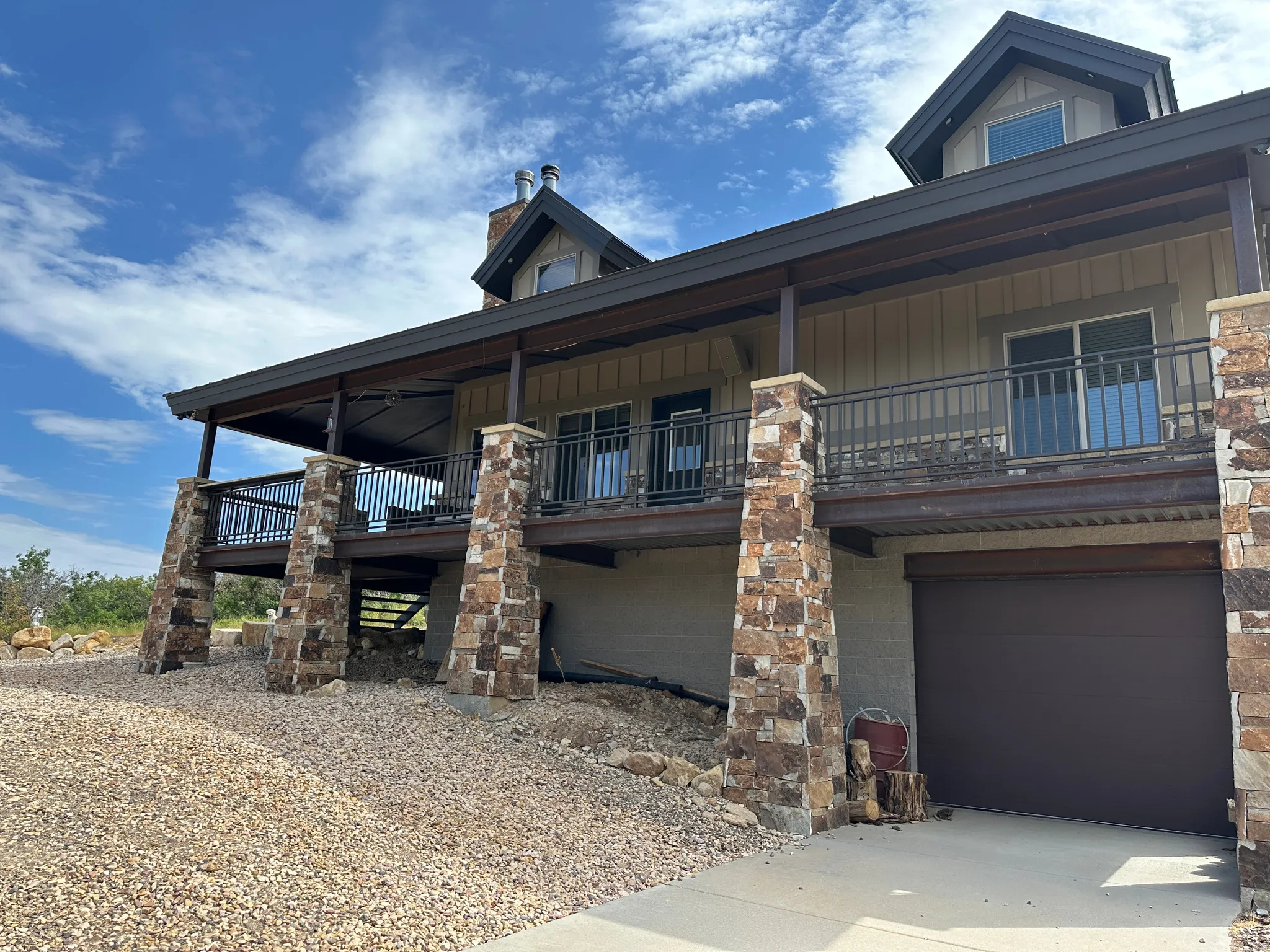 View of front facade with an attached garage, covered porch, driveway, and a chimney