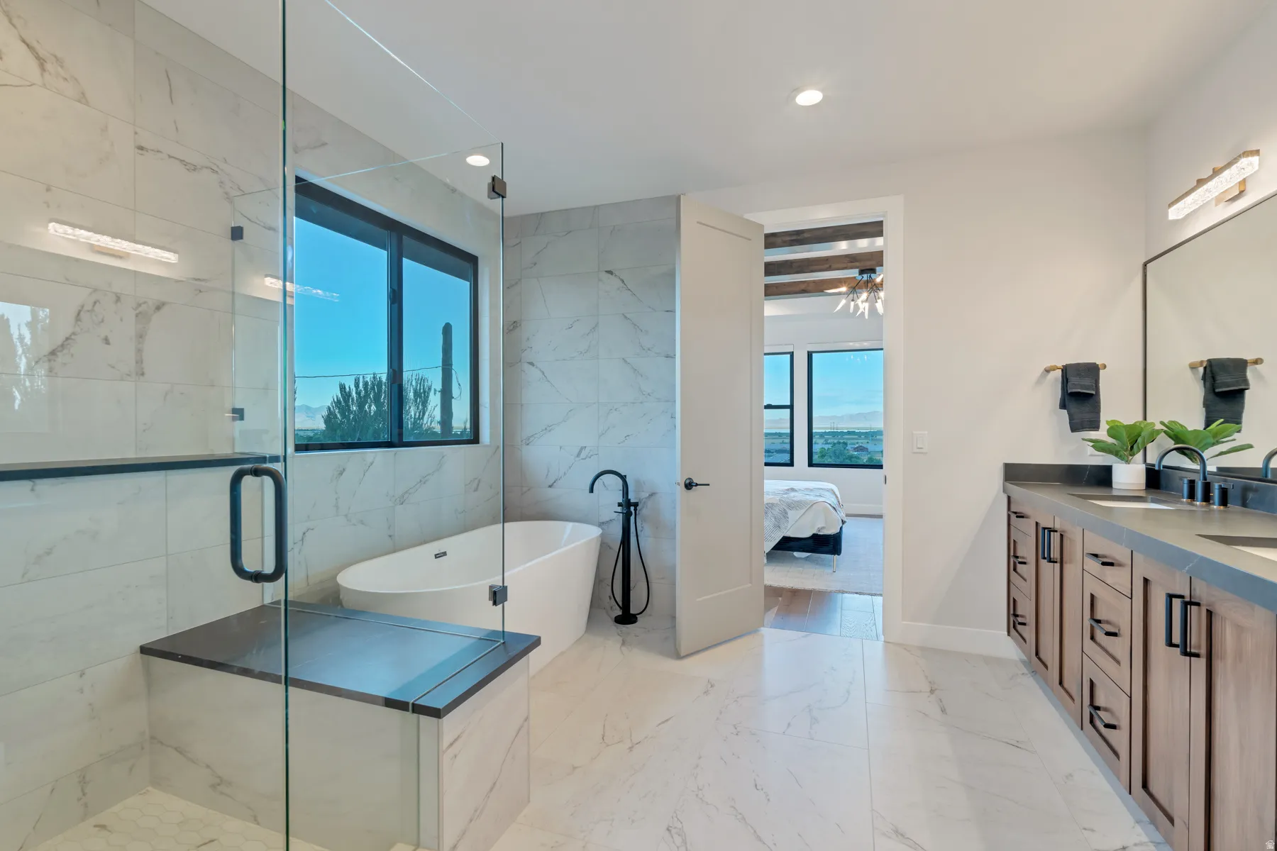 Bathroom featuring ensuite bathroom, plenty of natural light, a freestanding tub, double vanity, and tile walls