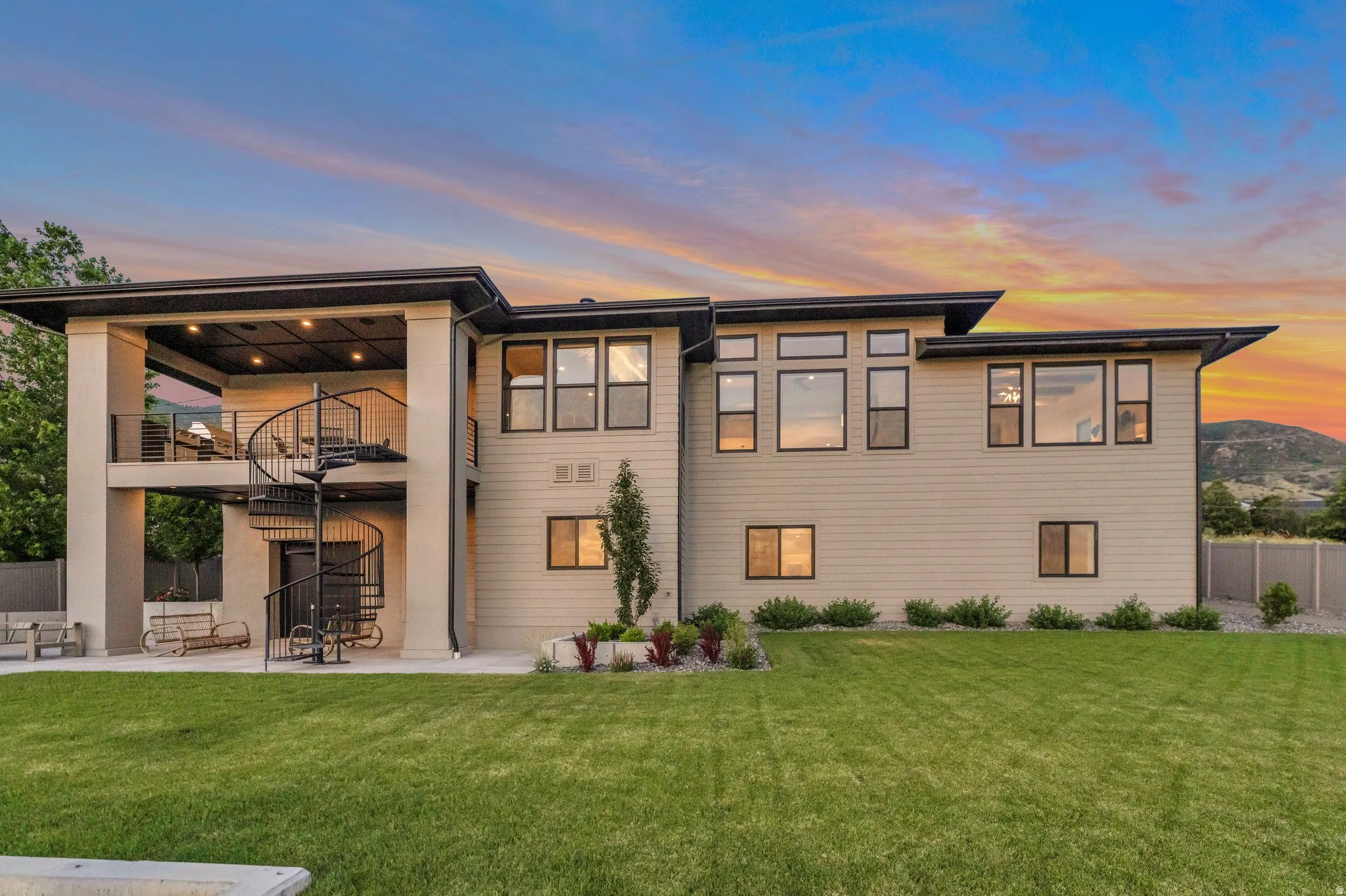 Back of house at dusk featuring a balcony and a patio area