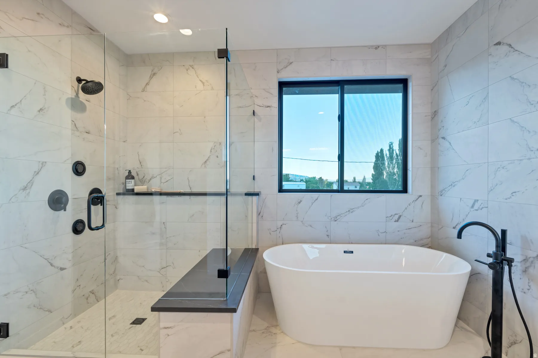 Full bathroom with a freestanding bath, a marble finish shower, tile walls, and marble tiled flooring