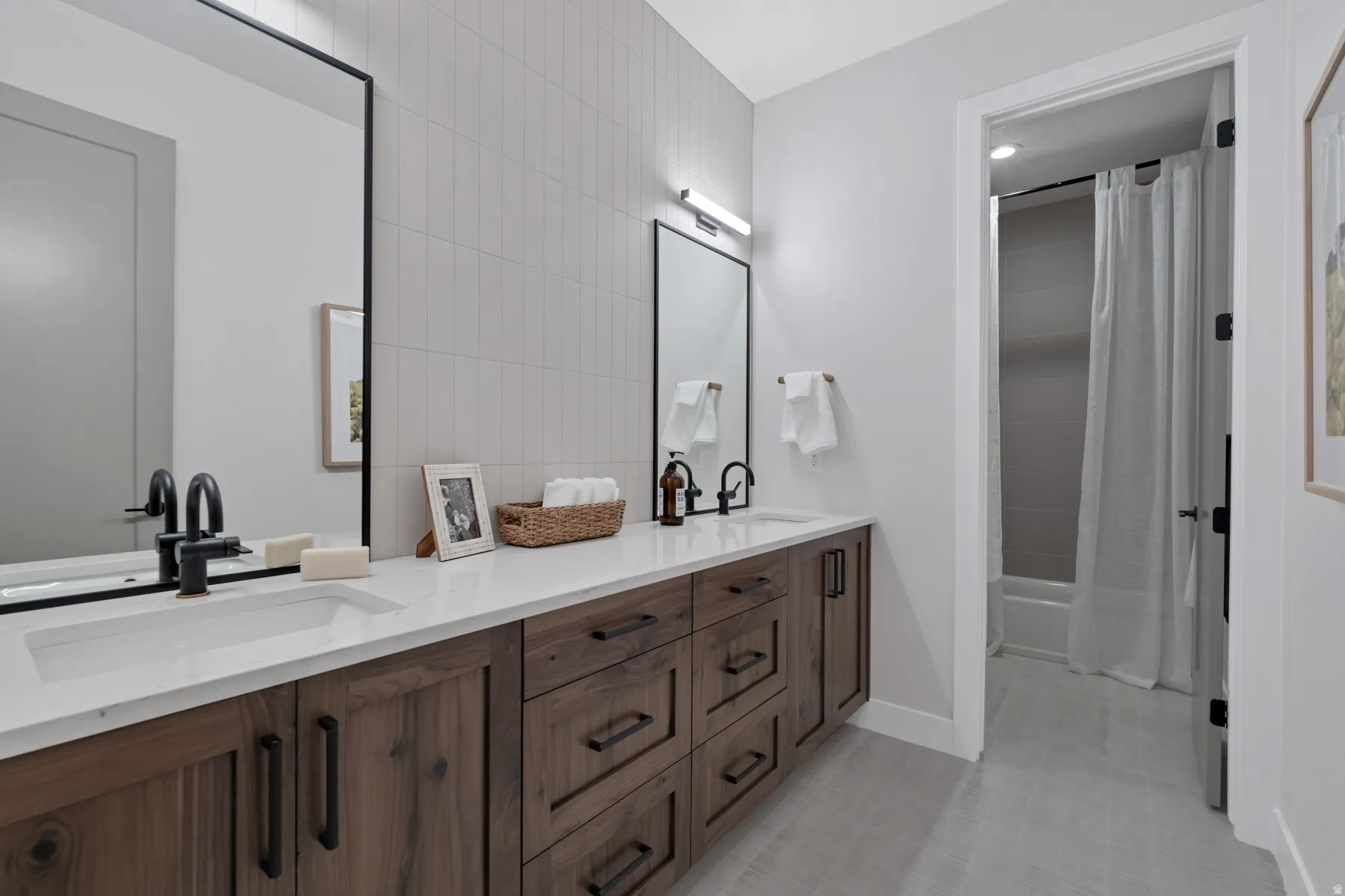 Bathroom with double vanity, shower / bath combo, and tile walls