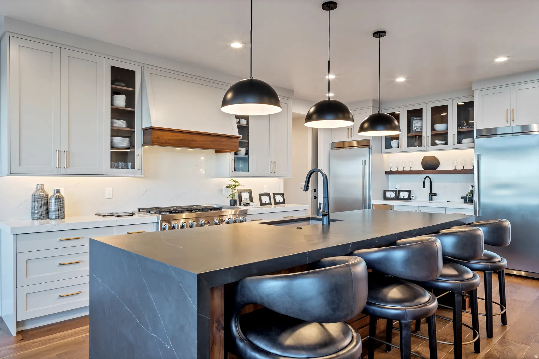 Kitchen featuring dark wood finished floors, built in fridge, a kitchen breakfast bar, and decorative light fixtures