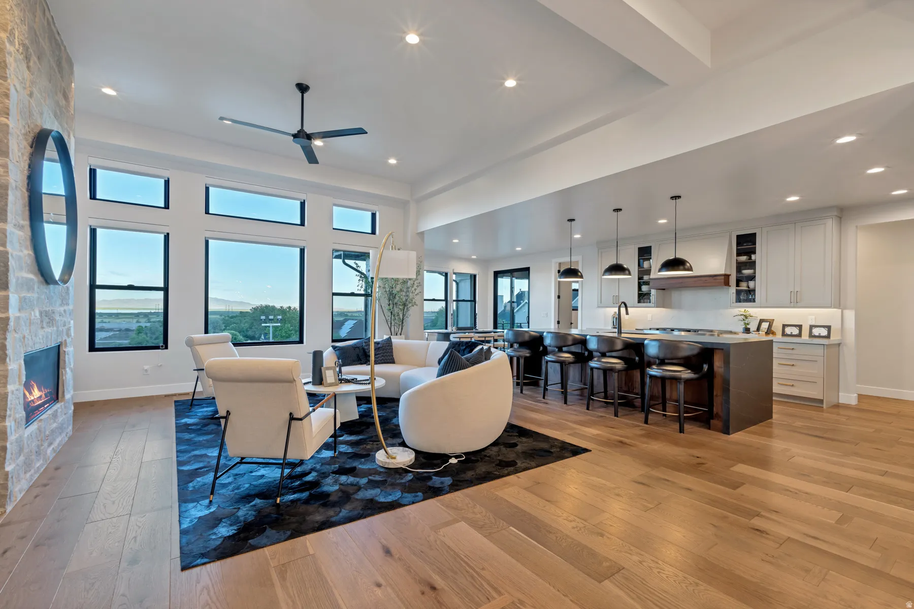 Living area with light wood-type flooring, a fireplace, ceiling fan, a high ceiling, and recessed lighting
