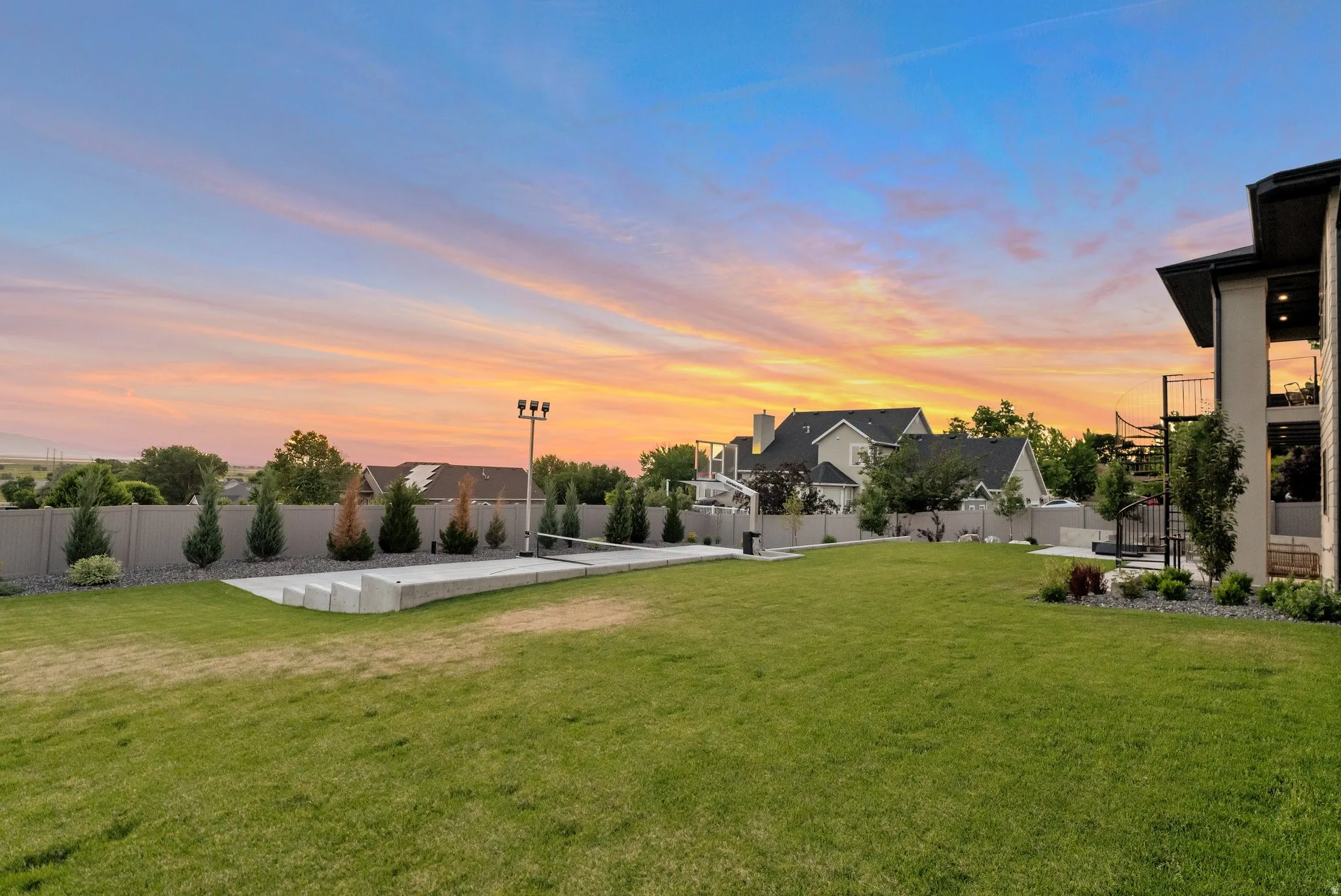Yard at dusk with a fenced backyard, volleyball court, and a residential view