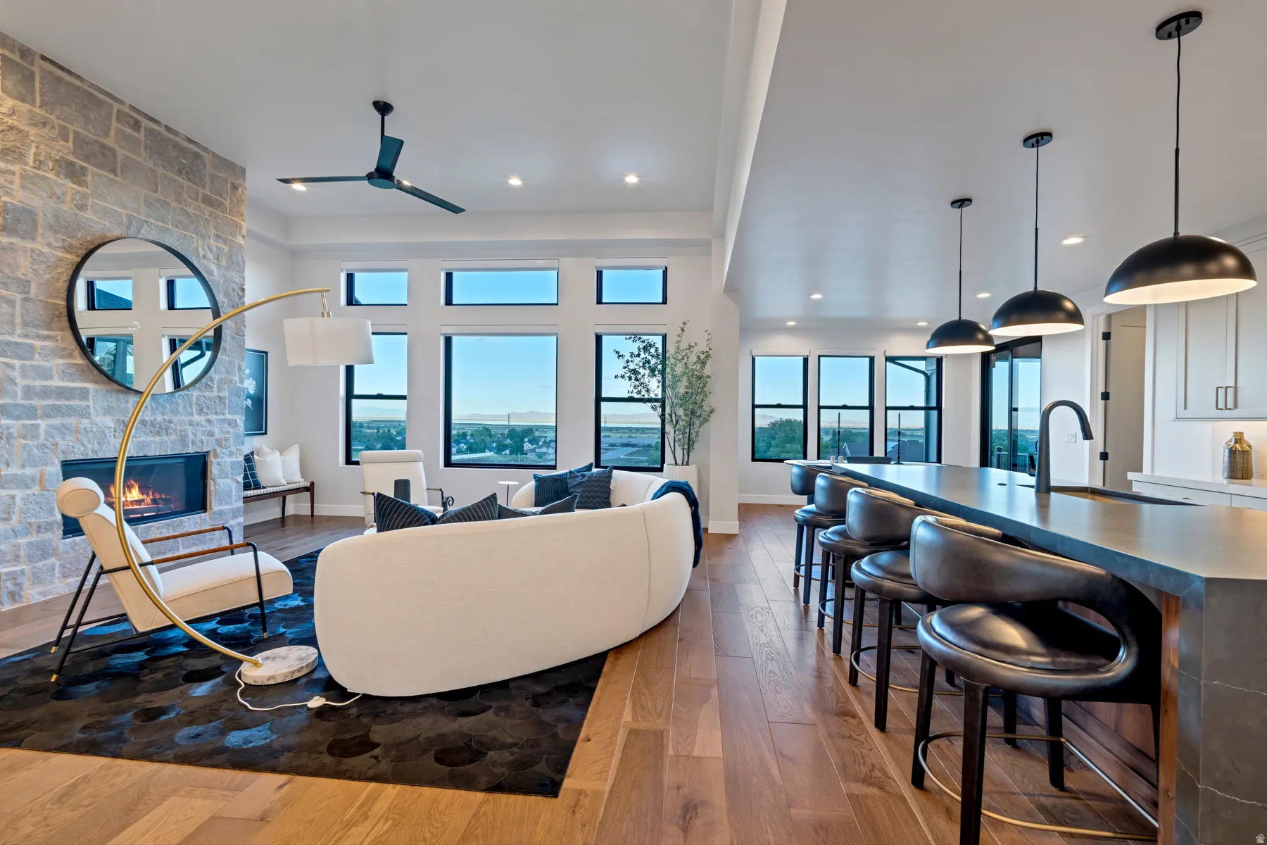 Living room featuring a stone fireplace, light wood-type flooring, and ceiling fan