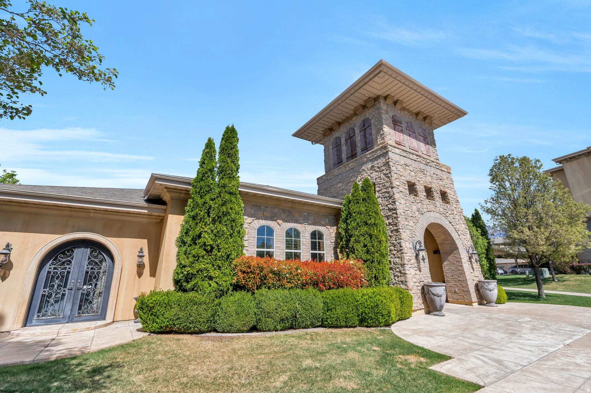 View of front facade featuring stone siding, a front lawn, french doors, and stucco siding
