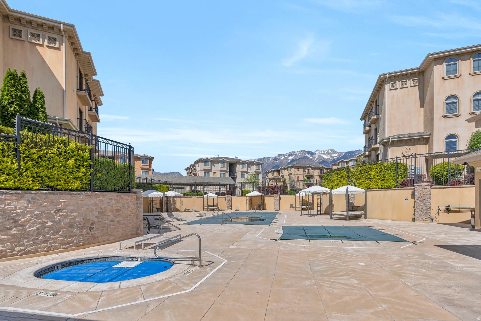 View of swimming pool featuring a hot tub, patio surround, a mountain view, and a residential view