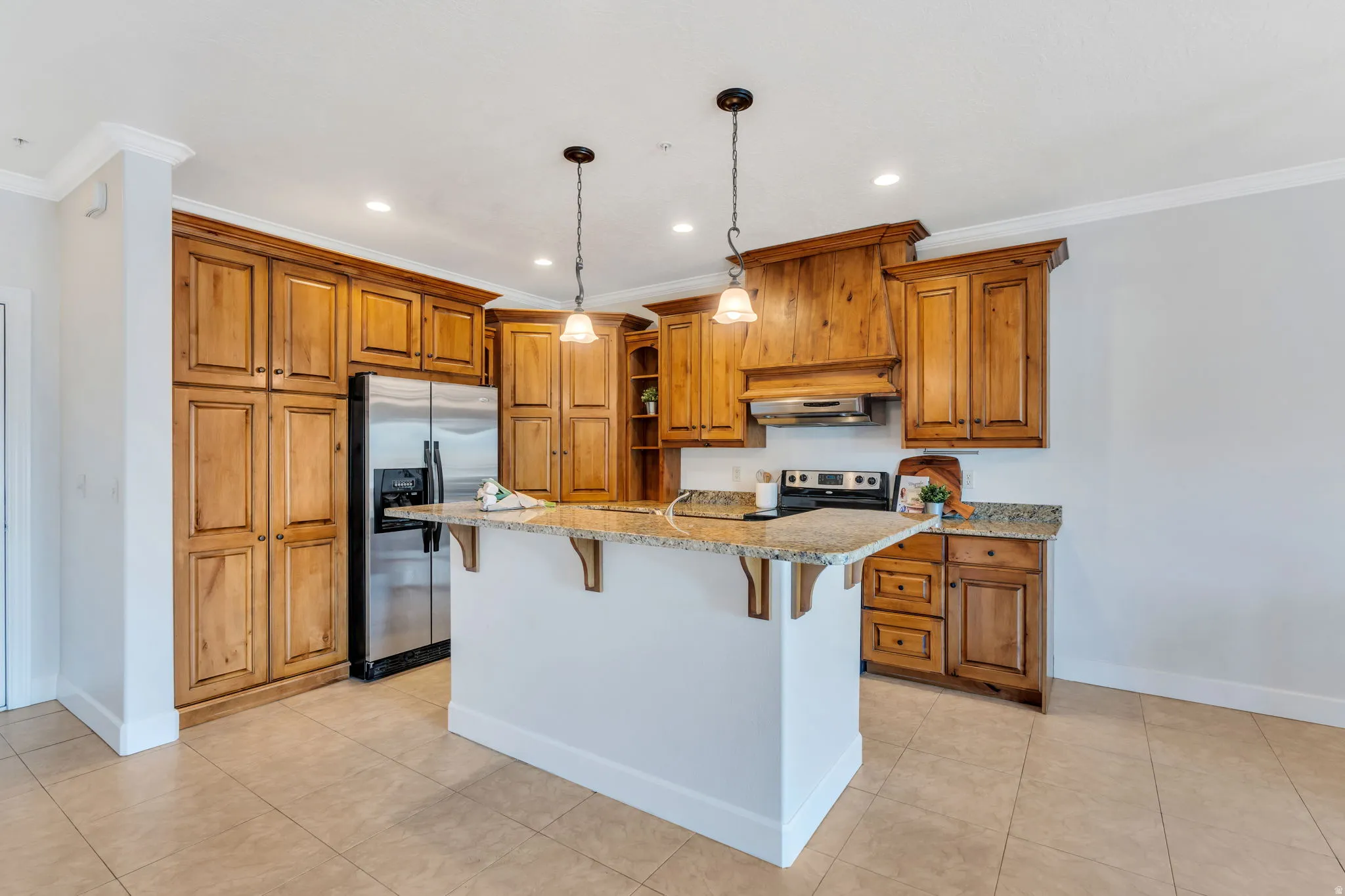 Kitchen featuring wood finish cabinets, a breakfast bar, stainless steel appliances, light stone countertops, and ornamental molding