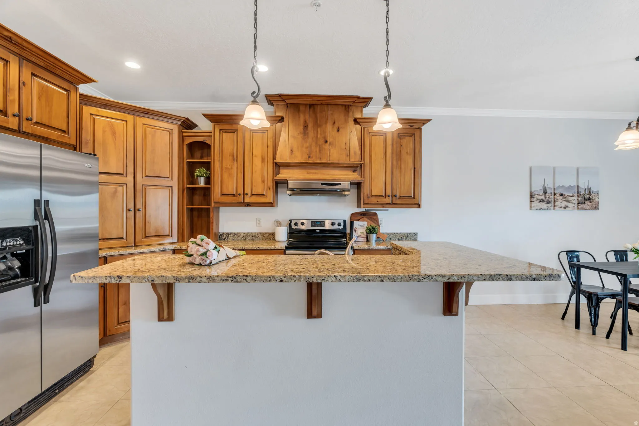 Kitchen with wood finish cabinets, a kitchen bar, crown molding, stainless steel appliances, and light stone counters
