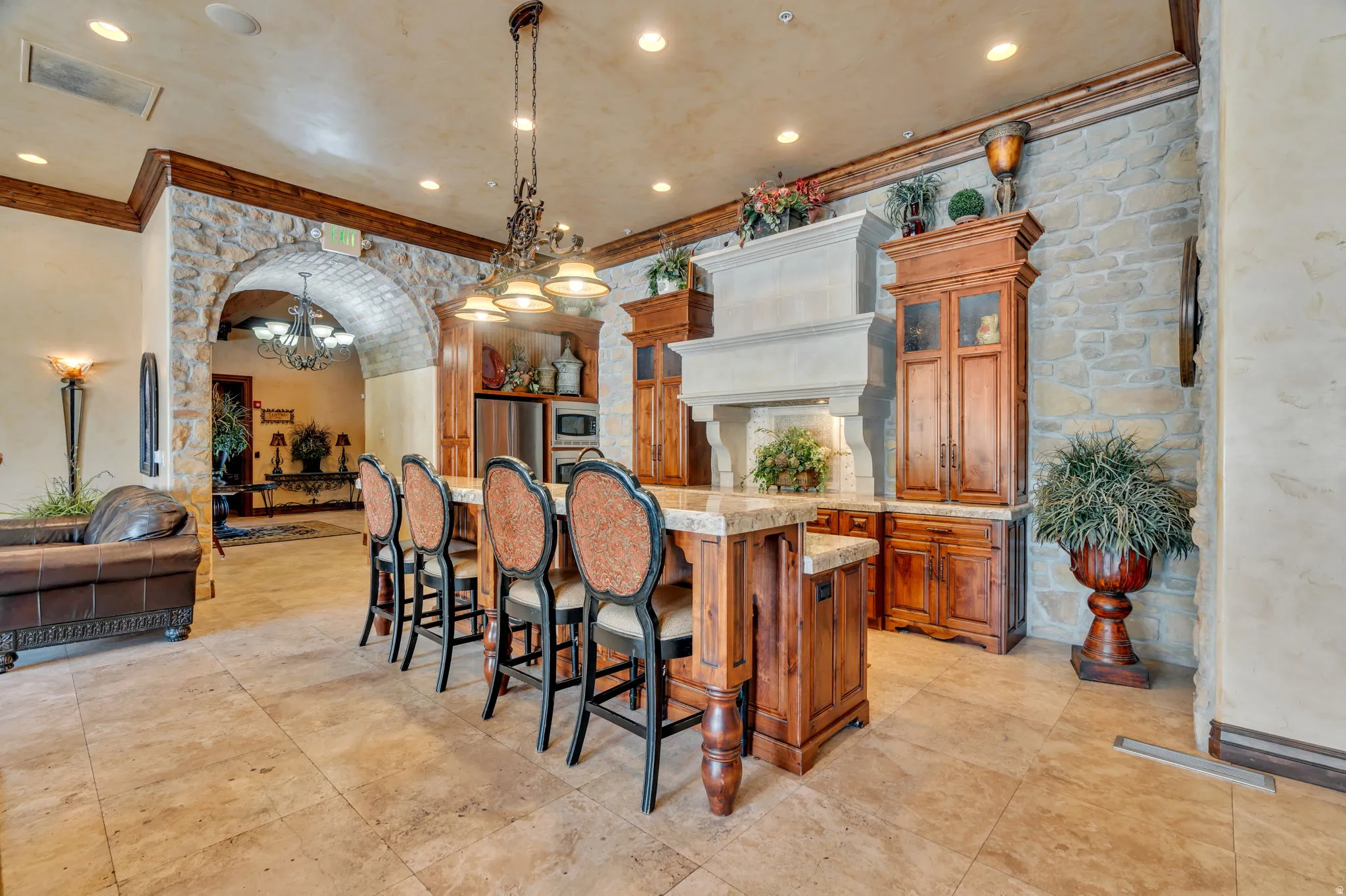 Kitchen featuring wood finish cabinets, arched walkways, a kitchen bar, ornamental molding, and glass fronted cabinets