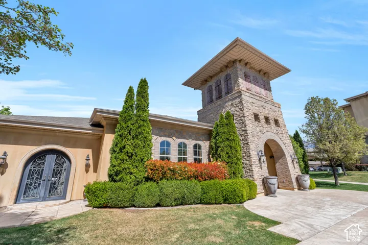 View of front facade featuring stone siding, a front lawn, french doors, and stucco siding