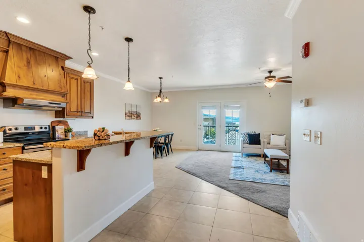Kitchen with wood finish cabinetry, light stone countertops, a breakfast bar area, ornamental molding, and electric stove