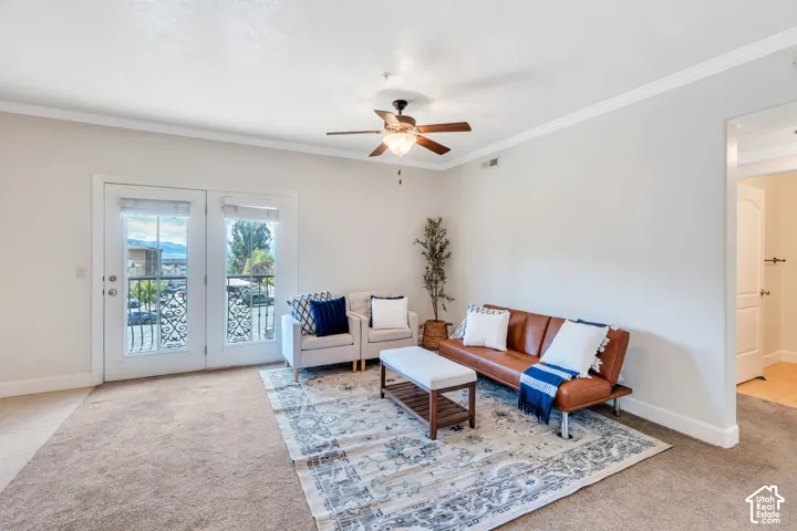 Living area featuring light carpet, ornamental molding, and a ceiling fan