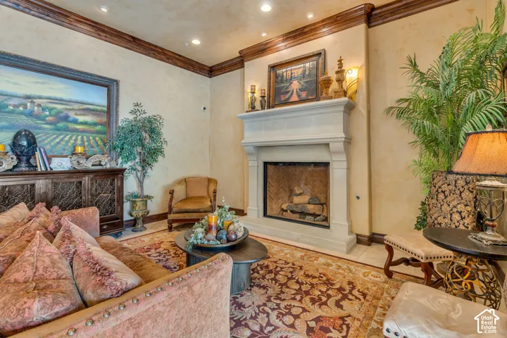 Tiled living area with a fireplace with raised hearth, recessed lighting, and crown molding