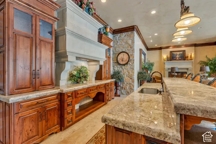 Kitchen featuring a fireplace, light stone counters, a kitchen bar, wood finish cabinets, and decorative light fixtures
