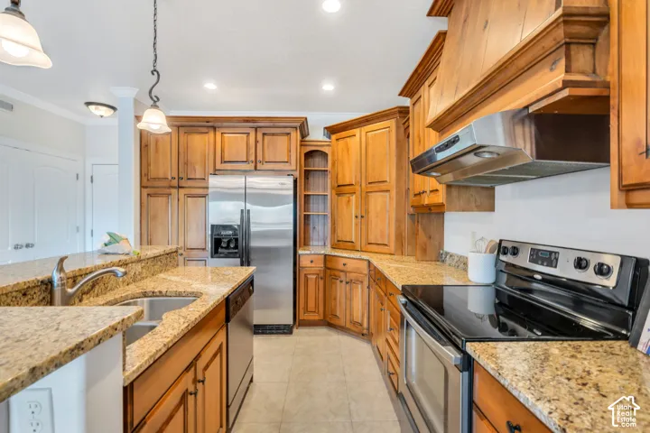 Kitchen with stainless steel appliances, light stone countertops, ornamental molding, and wood finish cabinetry