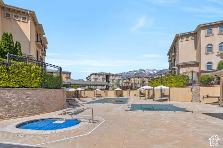 View of swimming pool featuring a hot tub, patio surround, a mountain view, and a residential view