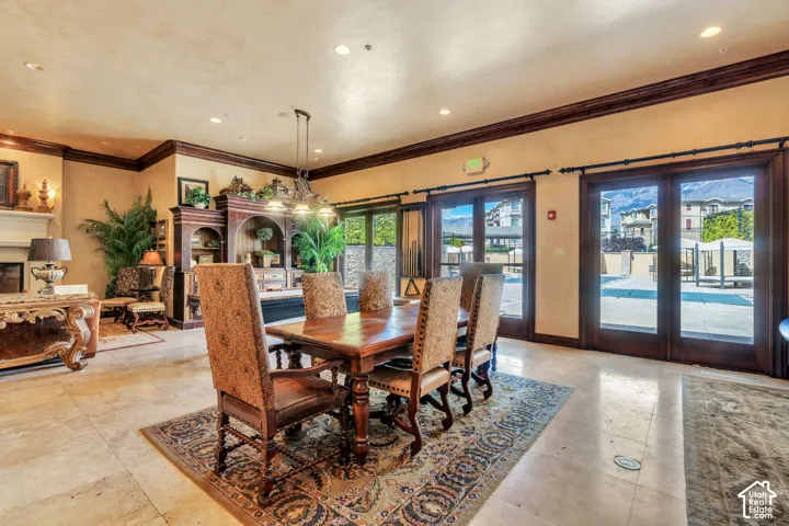 Dining space with a fireplace, crown molding, recessed lighting, and french doors