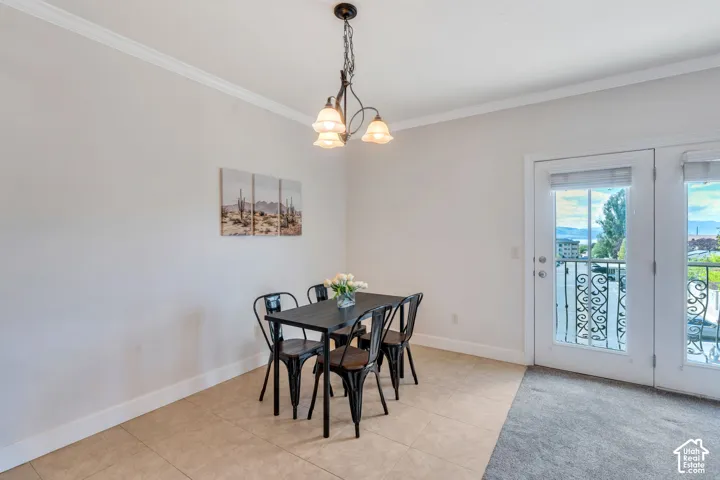 Dining room with crown molding, a chandelier, and light tile patterned flooring