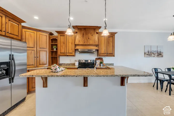 Kitchen with wood finish cabinets, a kitchen bar, crown molding, stainless steel appliances, and light stone counters