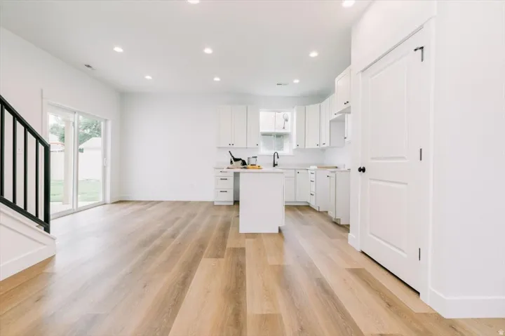 Kitchen with white cabinetry, light countertops, light wood finished floors, recessed lighting, and open floor plan