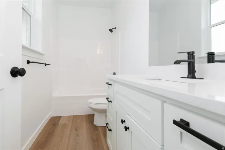 Full bath with healthy amount of natural light, vanity, light wood-style floors, and shower / bathtub combination