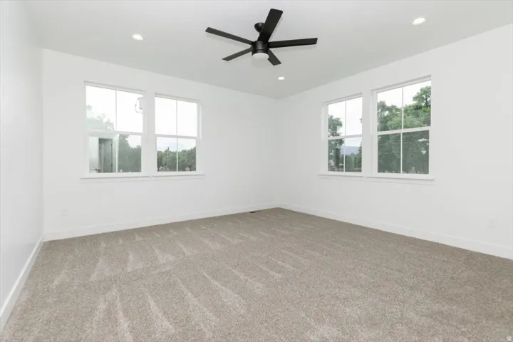 Carpeted spare room with ceiling fan and recessed lighting