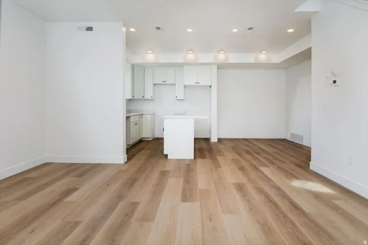 Kitchen with light countertops, light wood finished floors, recessed lighting, open floor plan, and white cabinets
