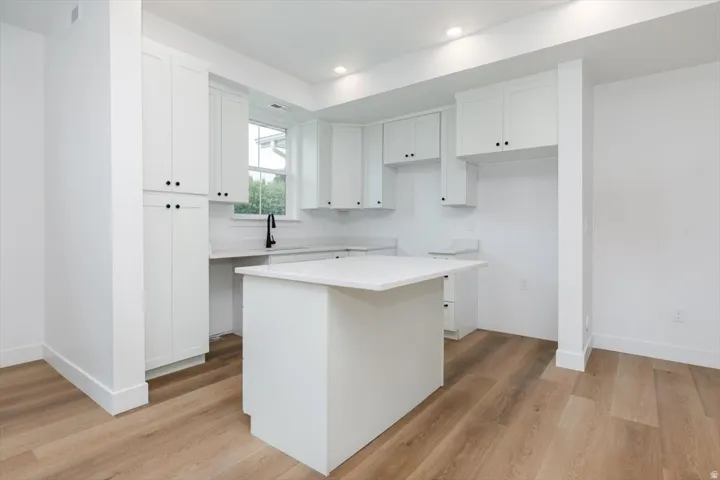 Kitchen featuring white cabinetry, light countertops, light wood-style flooring, a kitchen island, and recessed lighting