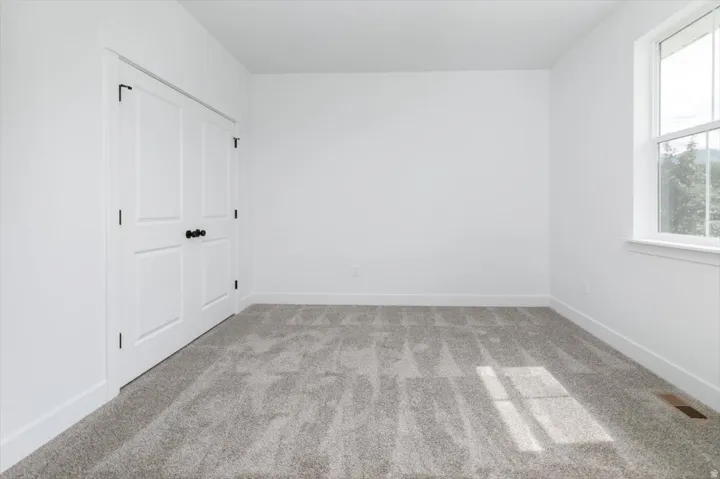 Unfurnished bedroom with light colored carpet and baseboards