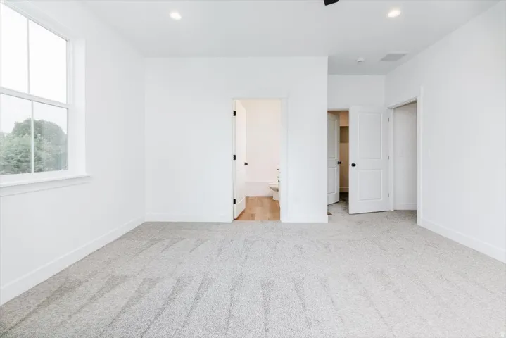 Unfurnished bedroom featuring ensuite bathroom, light colored carpet, recessed lighting, and ceiling fan