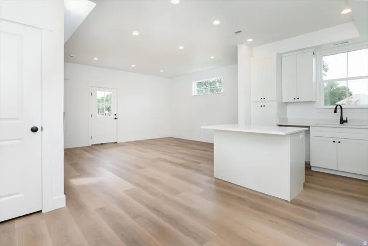 Kitchen with white cabinetry, recessed lighting, light wood-type flooring, and a center island