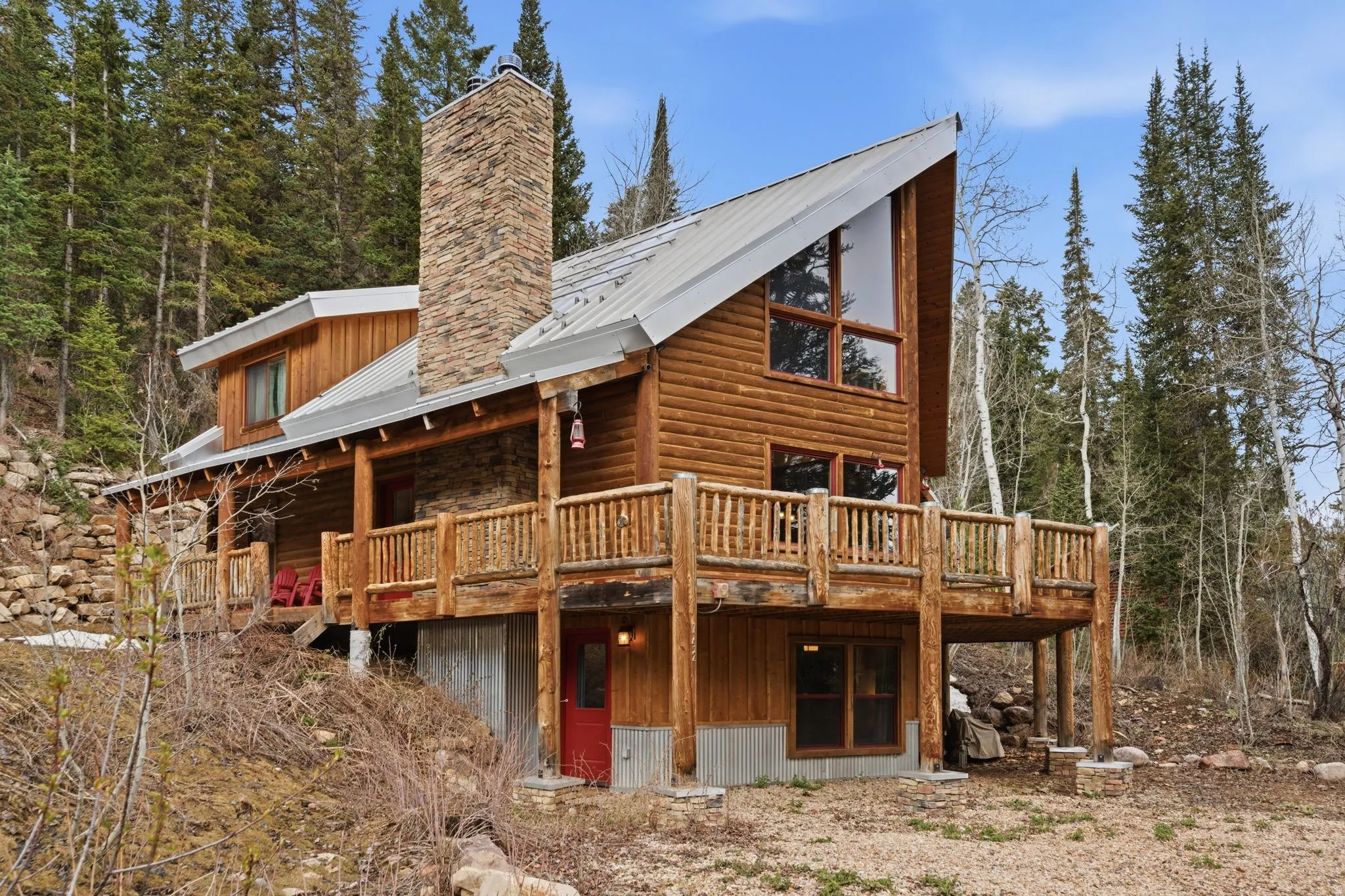 Back of house with a wooden deck, a chimney, and a metal roof