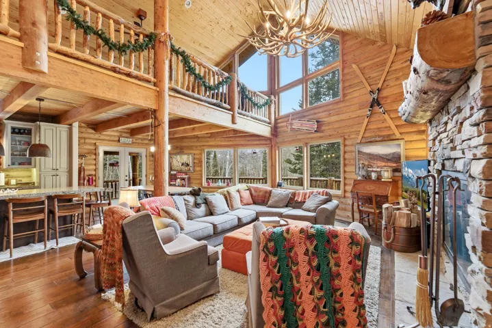 Living room featuring a vaulted wood ceiling, log walls, suspended lighting, hardwood / wood-style floors, and french doors