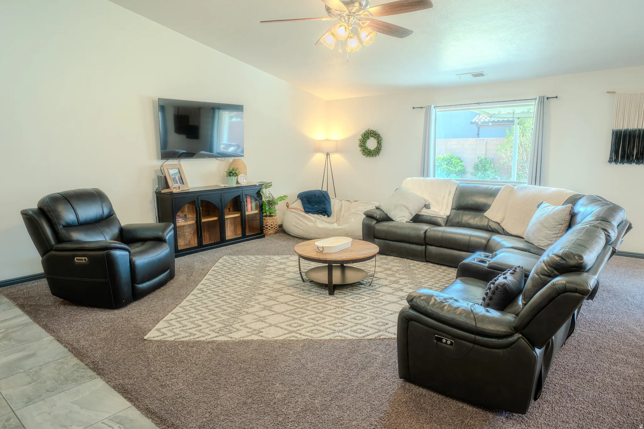Carpeted living area with lofted ceiling and ceiling fan