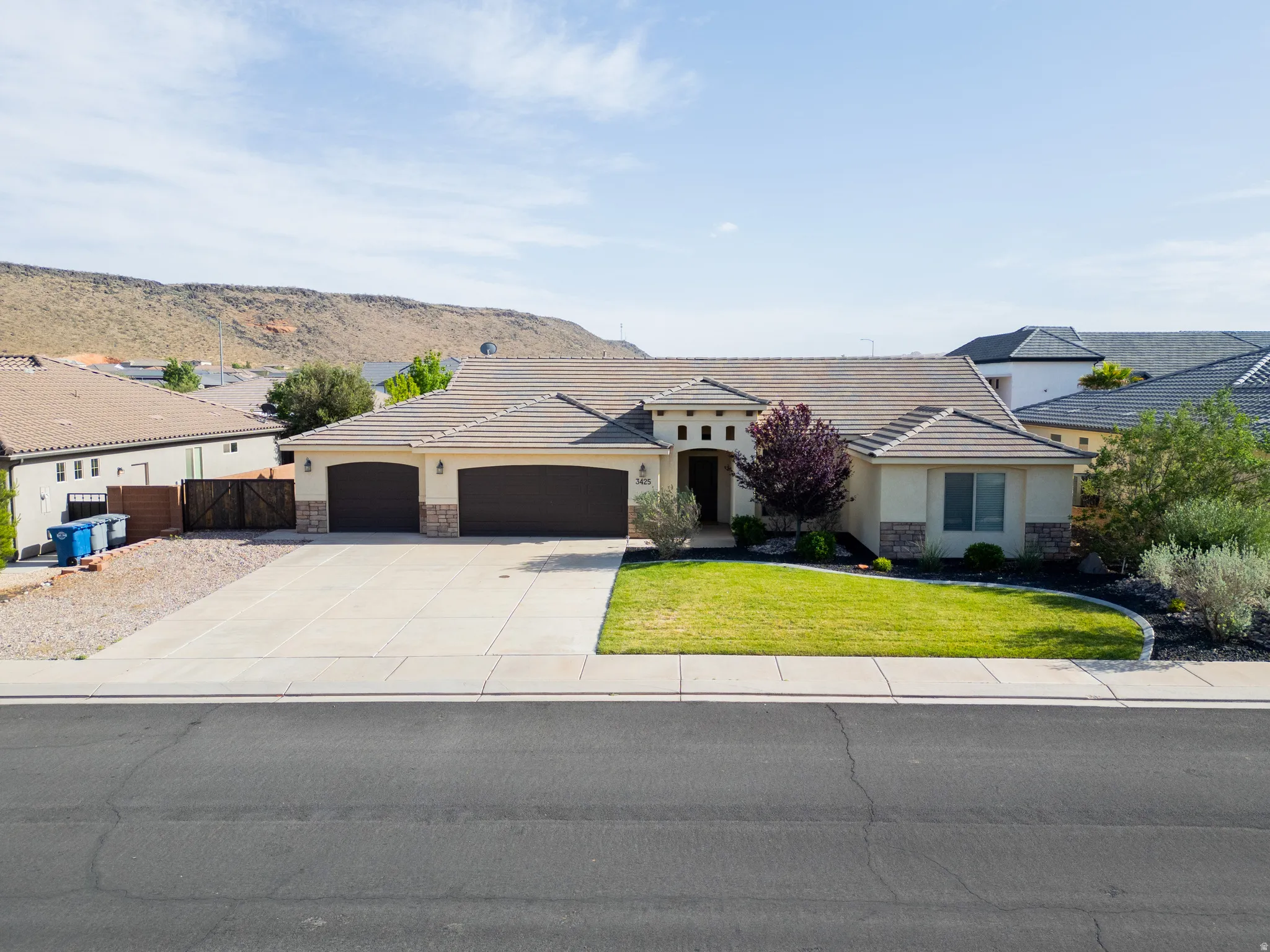 View of front of home with an attached garage, stone siding, stucco siding, driveway, and a front lawn