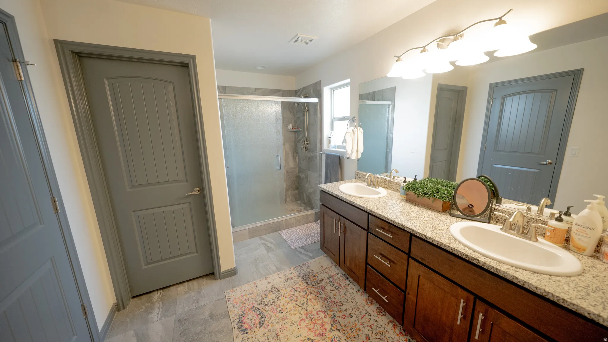 Full bath featuring double vanity and a stall shower