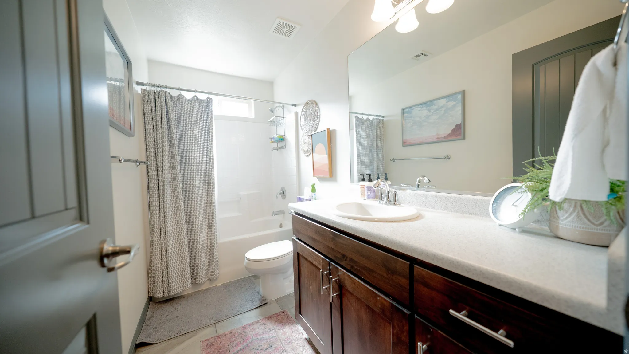 Full bath with vanity, shower / bath combo, and light tile patterned floors