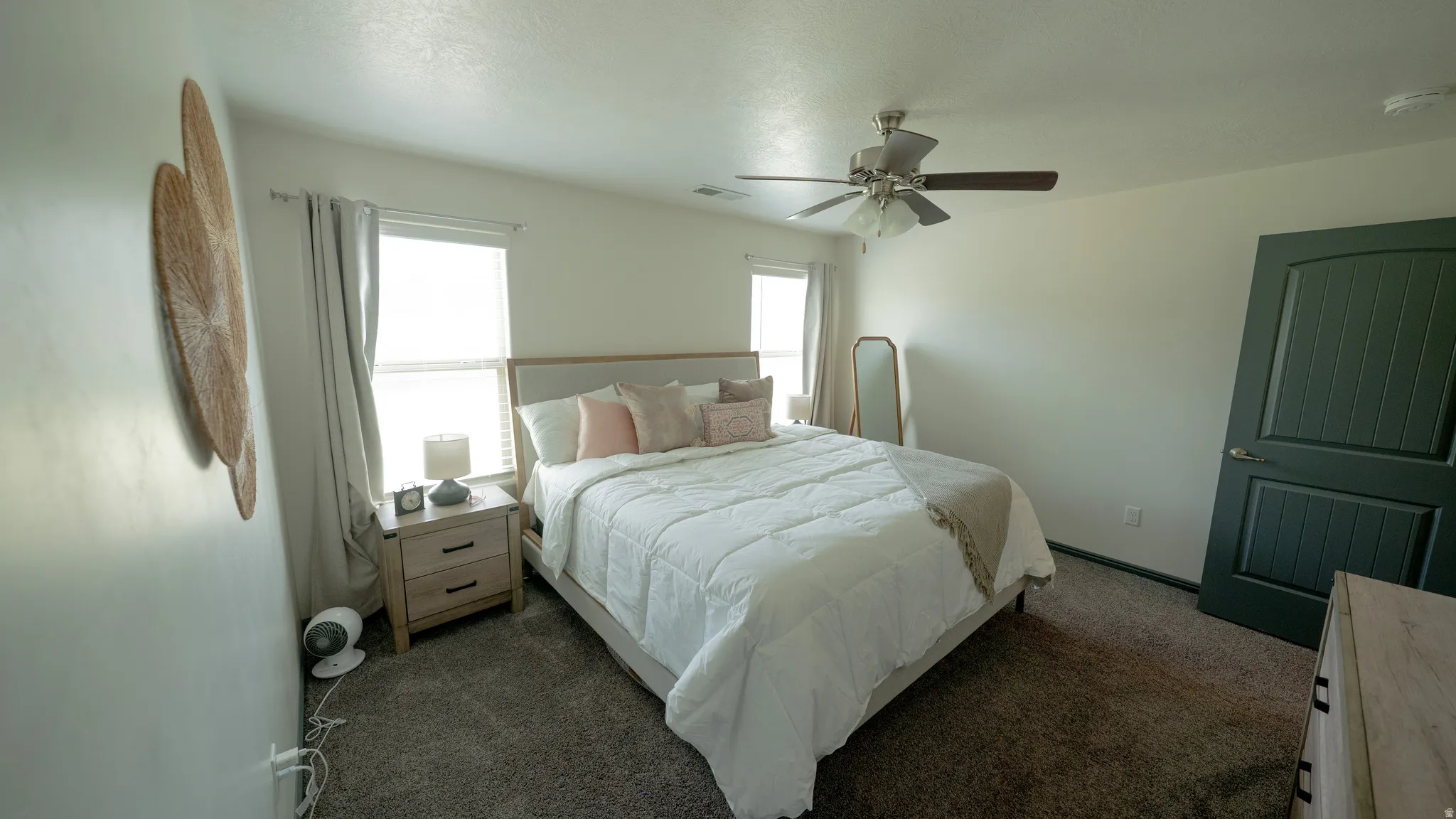 Bedroom with a ceiling fan and dark colored carpet