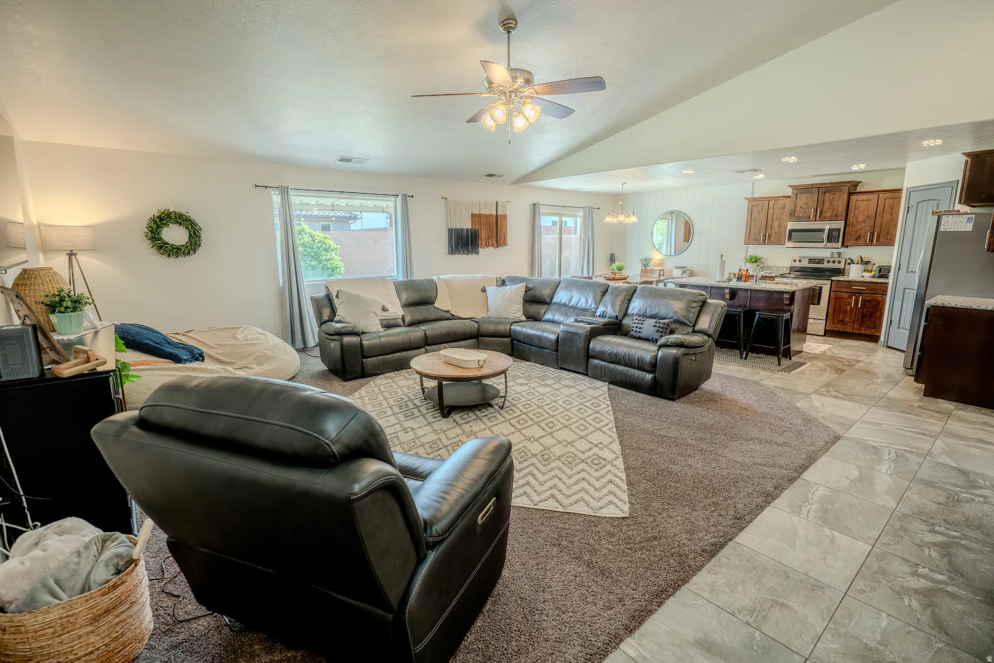Living room with ceiling fan, hanging lights, and vaulted ceiling
