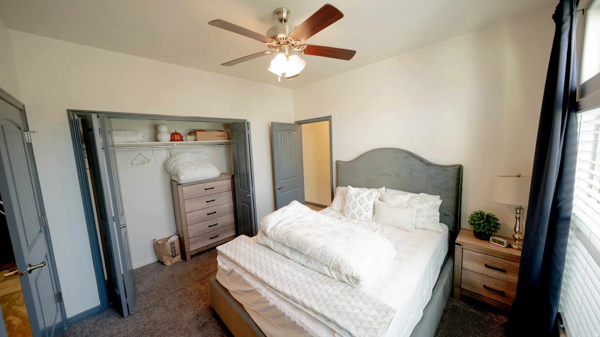 Bedroom with a closet, ceiling fan, and dark colored carpet