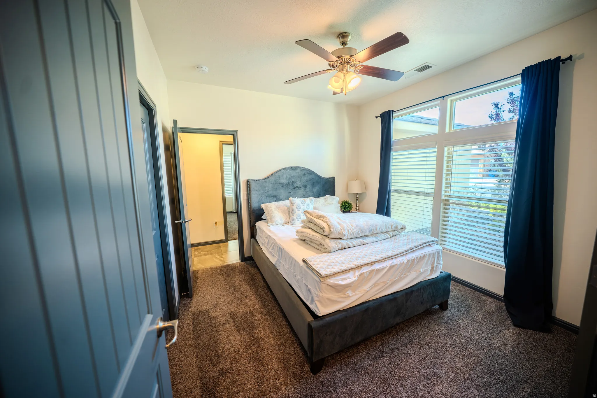Bedroom with a ceiling fan and dark carpet