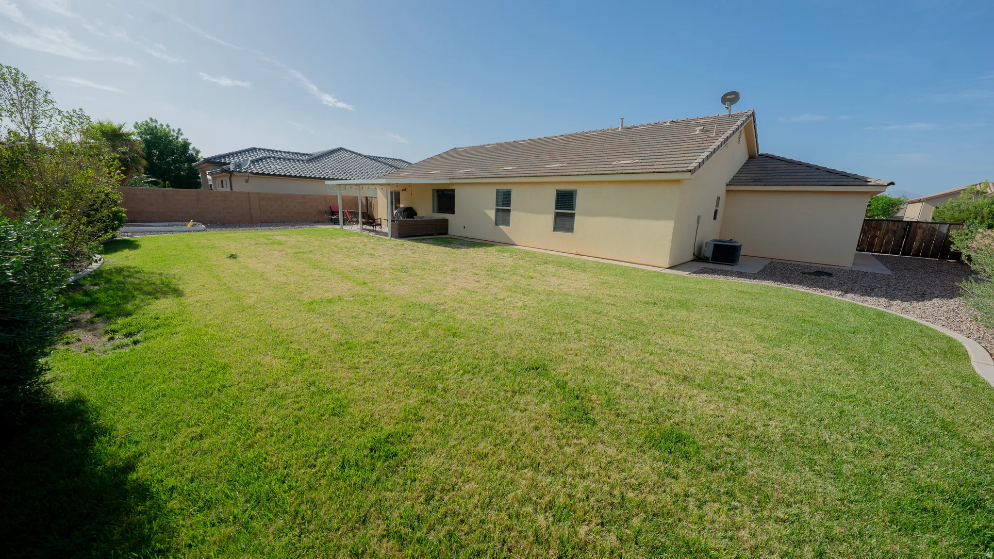 Back of house featuring a fenced backyard, stucco siding, a patio area, and a tiled roof