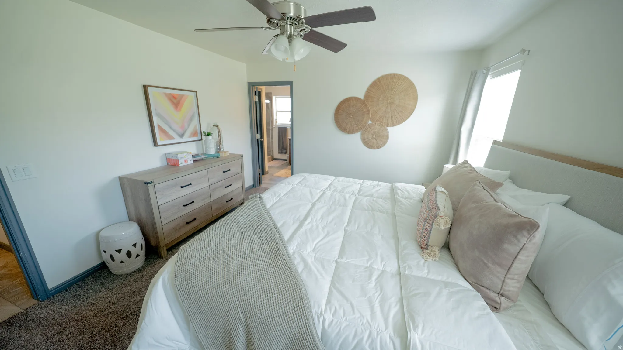 Bedroom with ensuite bathroom, a ceiling fan, and light carpet