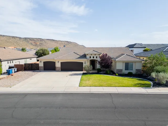 View of front of home with an attached garage, stone siding, stucco siding, driveway, and a front lawn