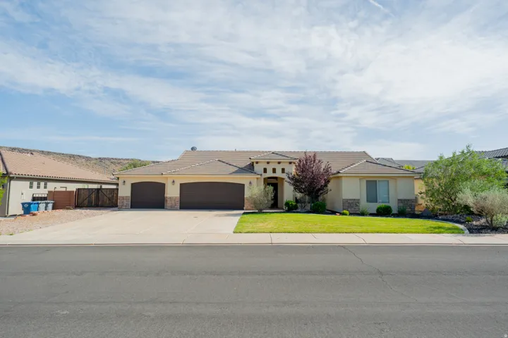 View of front of house with stone siding, stucco siding, an attached garage, and concrete driveway