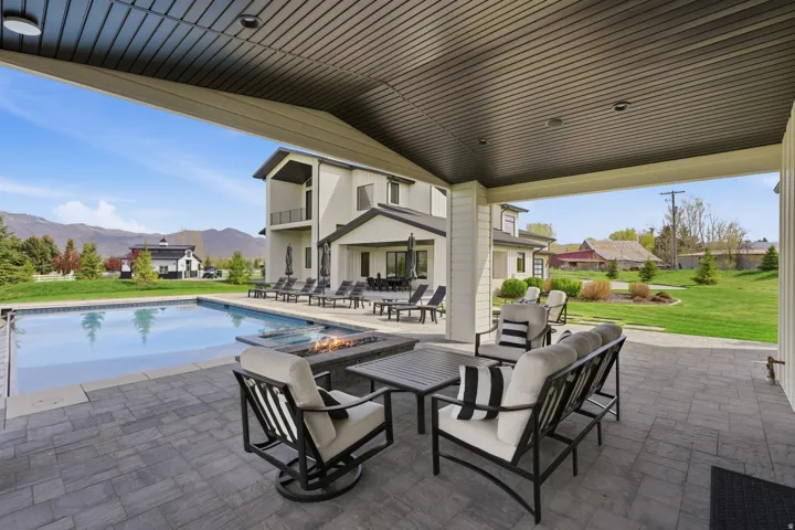 View of patio with an outdoor living space with a fire pit, a mountain view, and a pool with connected hot tub