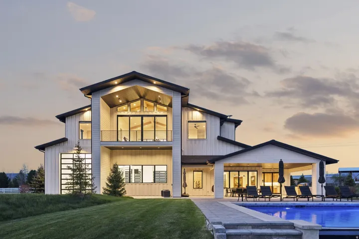 Back of property with a balcony, a patio area, an outdoor pool, a yard, and board and batten siding
