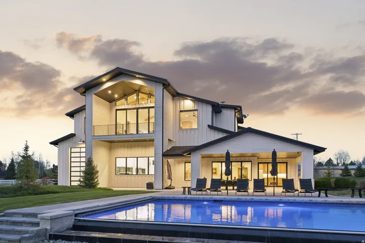 Back of property with a balcony, a patio area, an outdoor pool, and board and batten siding
